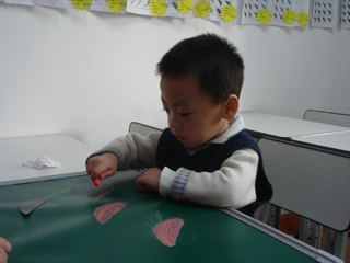 小朋友在小黑板上用粉笔练习描红