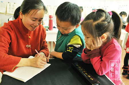 幼儿班的小同学在周老师的指导下学习硬笔字